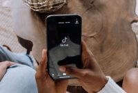 Ilustrasi aplikasi TikTok di layar ponsel yang digunakan untuk membuat konten promosi melalui program TikTok Affiliate dengan bantuan teknologi AI video generator. (Sumber: Pexels/cottonbro studio)